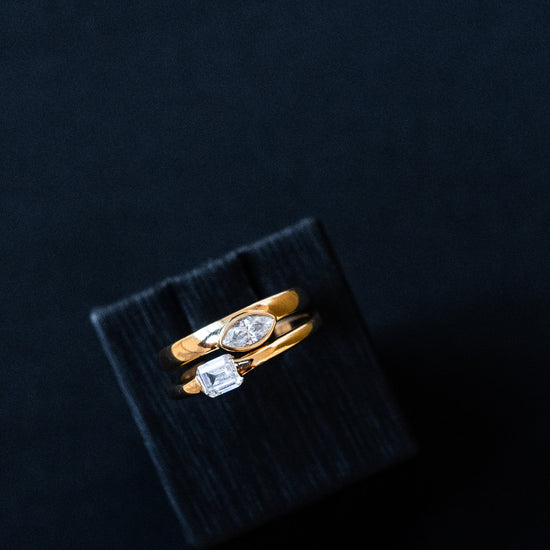 Amorati Diamonds Asymmetrical Horizontal Stacking Ring stacked with Whispering Signet Ring on a layflat.