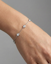 A full top-down view of a 14K white gold bracelet, showing the spaced-out, bezel-set diamonds on the delicate chain on figure.