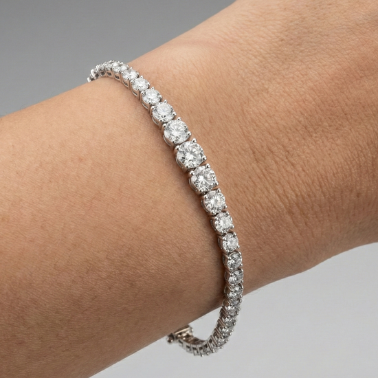A full top-down view of a 14K white gold tennis bracelet, coiled to show the cascading line of round diamonds and the clasp on wrist.