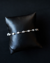 White gold Amorati eternal diamond strand bracelet displayed on a black jewelry cushion.