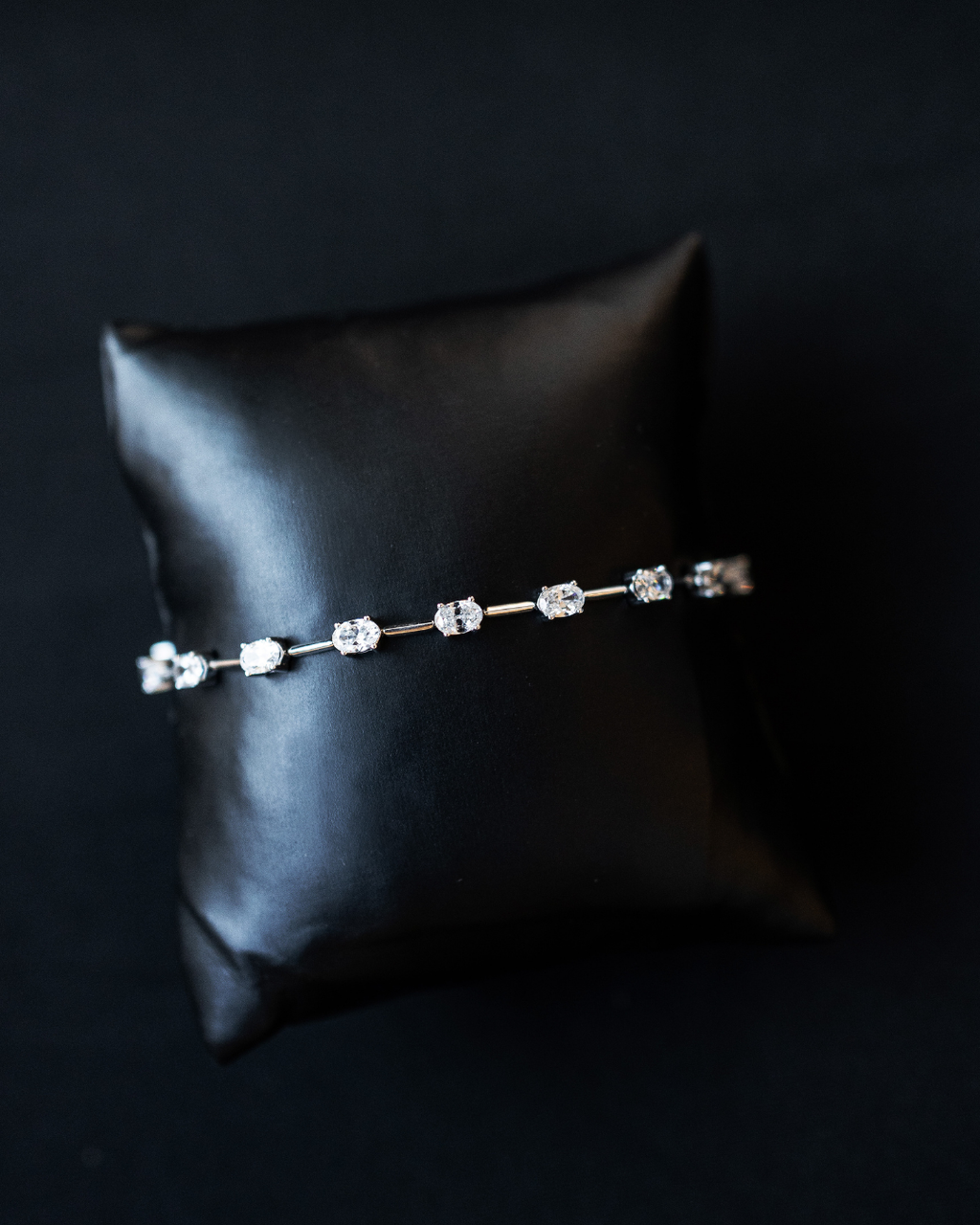 White gold Amorati eternal diamond strand bracelet displayed on a black jewelry cushion.