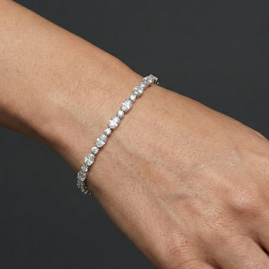 White gold oval diamond tennis bracelet worn on the wrist, draping naturally and offering elegant sparkle with a refined silhouette.