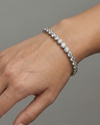 A full top-down view of a 14K white gold tennis bracelet, coiled to show the seamless circle of brilliant diamonds on wrist.