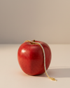 A view of the 14K yellow gold tennis bracelet, coiled to show the continuous, brilliant line of diamonds on a red apple.
