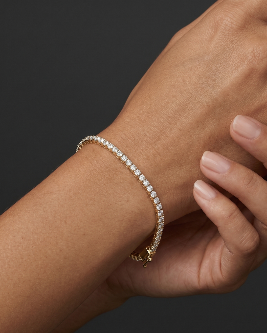 Close-up lifestyle view of a classic 14k rose gold tennis bracelet featuring a continuous, uniform row of brilliant round-cut diamonds styled on a wrist.
