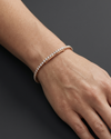 Close-up lifestyle view of a classic 14k rose gold tennis bracelet featuring a continuous, uniform row of brilliant round-cut diamonds styled on a wrist.
