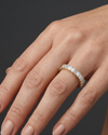 Lifestyle view of a model wearing a luxurious 14k yellow gold eternity ring fully set with a continuous row of shimmering emerald-cut diamonds.