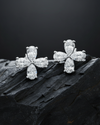 Two diamond flower studs are resting on a textured, dark gray rock to highlight their sparkle.