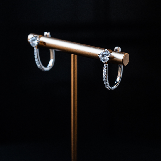 White gold Amorati cascade drop diamond hoop earrings displayed on a gold jewelry stand.