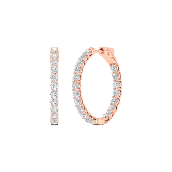 A close-up of a pair of 14K rose gold huggie hoop earrings with a continuous line of brilliant round-cut diamonds, shown on a black background to highlight their sparkle.