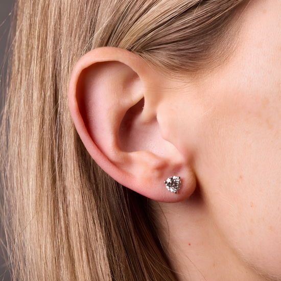 Amorati Bold 1.0 cttw Martini-set stud earring on model view of a 10K white gold three-prong .24 ct total weight diamond stud earrings, shown on the left ear.