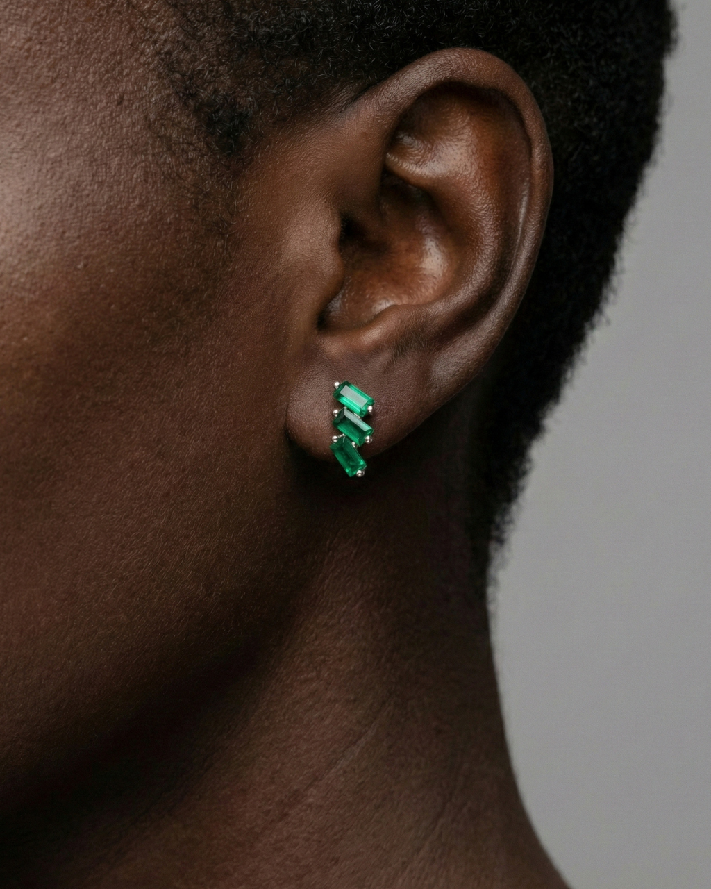 A close-up, profile shot of a person’s ear and jawline, showcasing the Cascading Baguette-Cut Stud Earrings. The model’s hair is swept back, allowing the jewelry to take center stage against a soft-focus, neutral background.