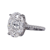 Close-up angled view of a silver-toned engagement ring featuring a large oval-cut center diamond in a four-prong setting, with a pavé diamond band, set against a transparent checkerboard background.
