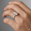 Pear cut diamond engagement ring in 14k white gold with a prong diamond band and twist setting on a hand