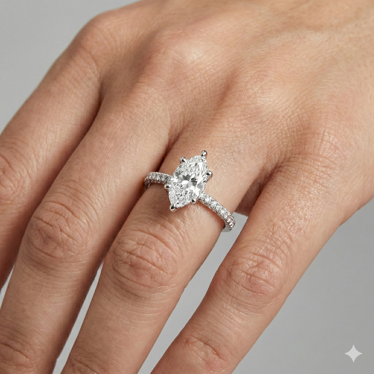 Marquise cut diamond engagement ring in 14k white gold with a pavé diamond band and cathedral setting on a hand