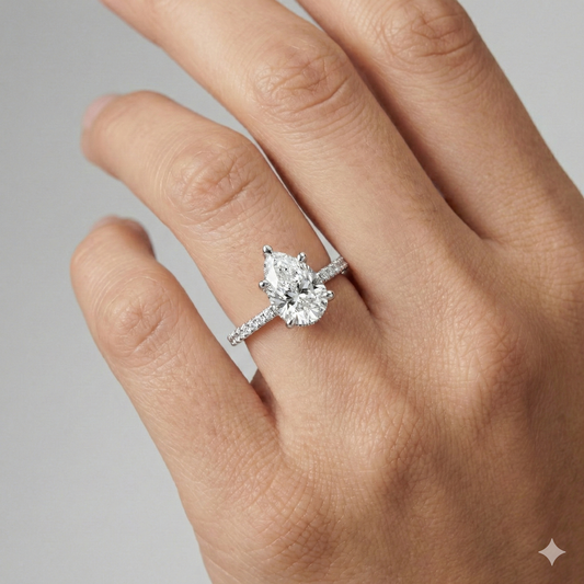 Pear cut diamond engagement ring in 14k white gold with a pavé diamond band and cathedral setting on a hand