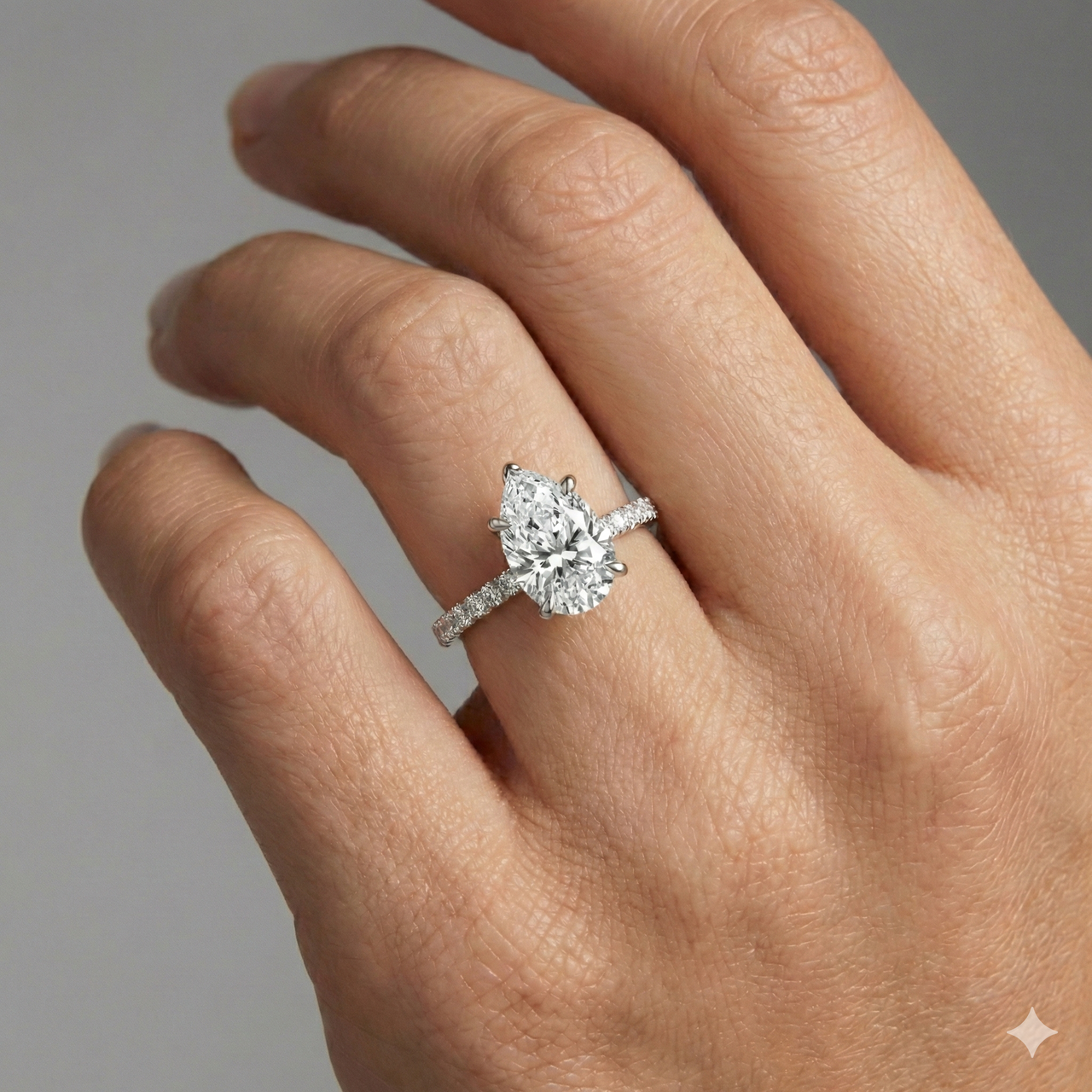 Pear cut diamond engagement ring in 14k white gold with a prong diamond band and cathedral setting on a hand