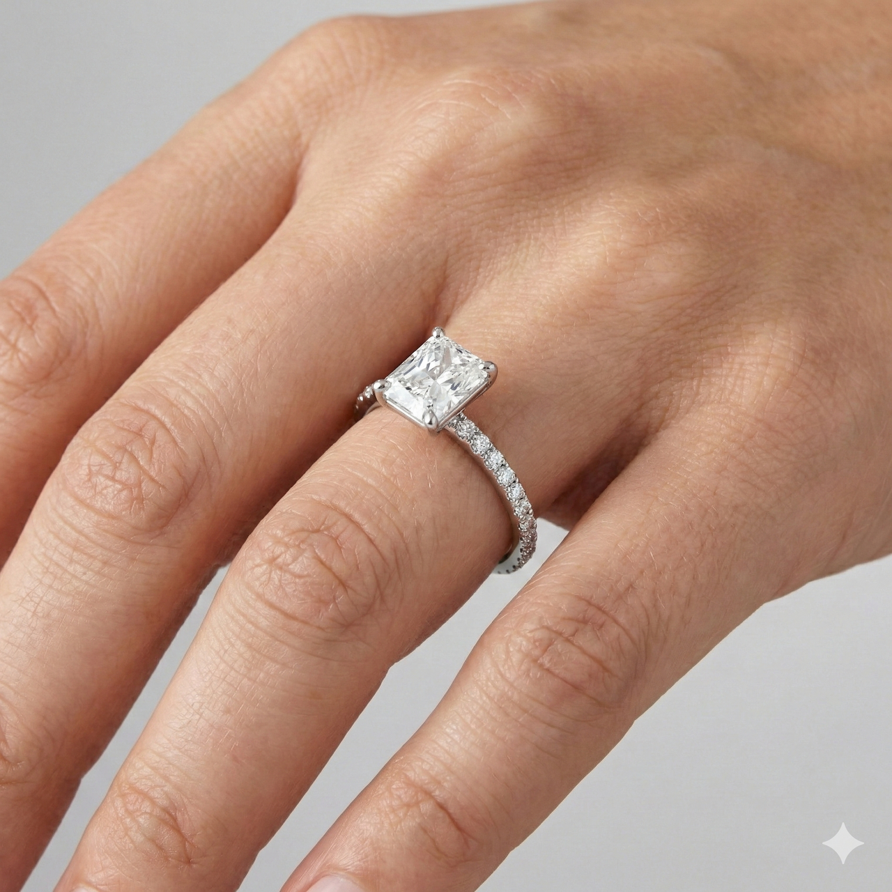 Radiant cut diamond engagement ring in 14k white gold with a prong diamond band and cathedral setting on a hand