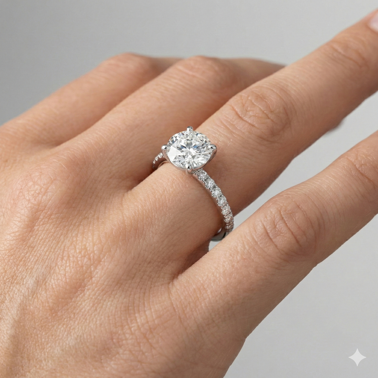 Round cut diamond engagement ring in 14k white gold with a prong diamond band and cathedral setting on a hand