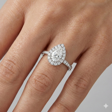 14K white gold pear halo engagement ring worn on hand featuring pear center diamond, round halo and channel set diamond band in cathedral setting.