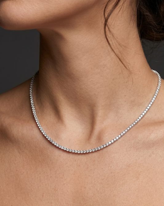 Lifestyle view of a model wearing a classic white gold or platinum tennis necklace featuring a continuous uniform strand of brilliant round-cut diamonds.