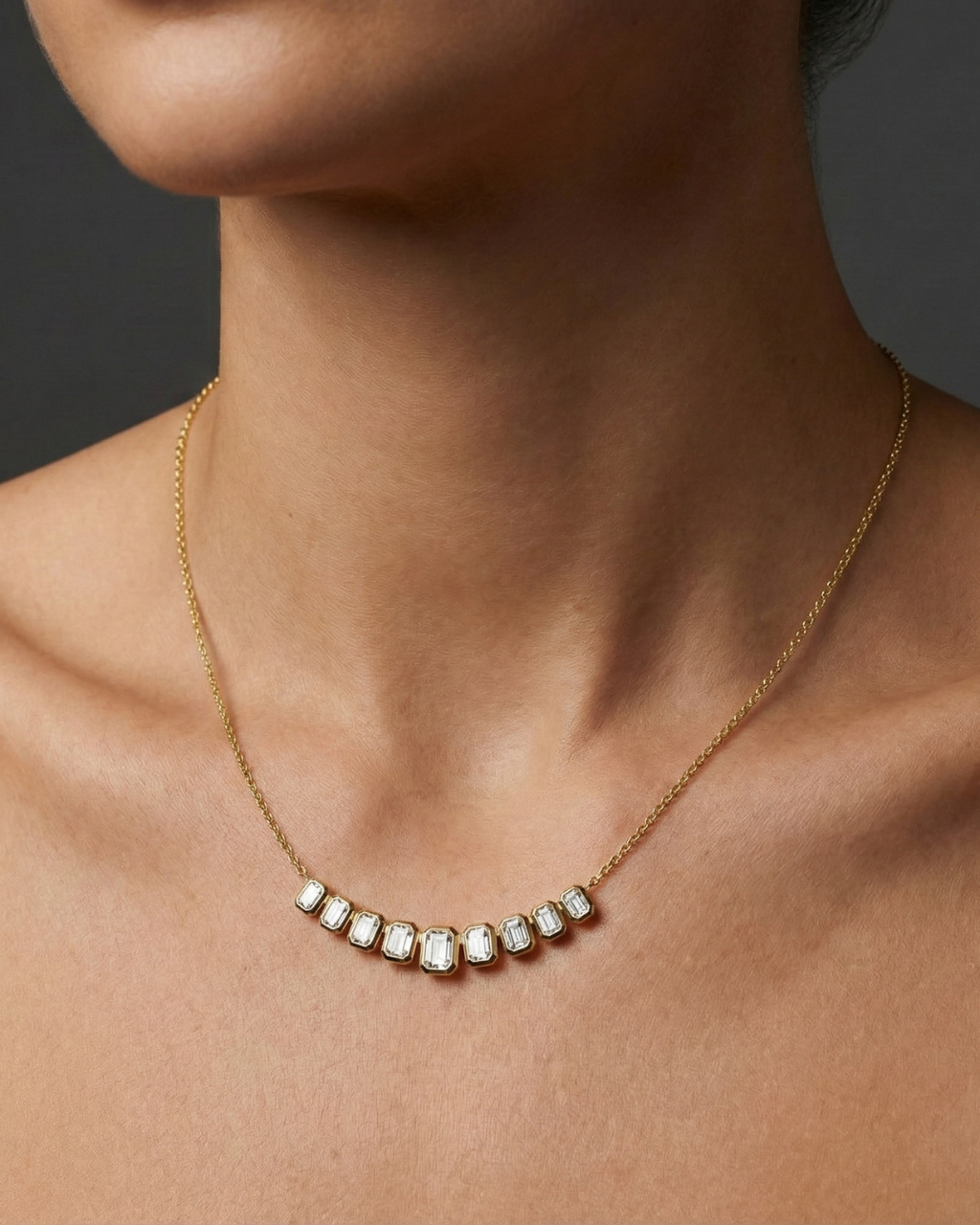 Yellow gold smaller emerald-cut diamond necklace worn on figure, offering a warm glow and effortlessly minimal sophistication.