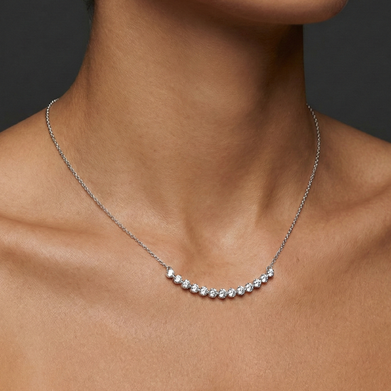 Lifestyle view of a white gold necklace worn on the neck, showcasing round white diamonds along a curved design.