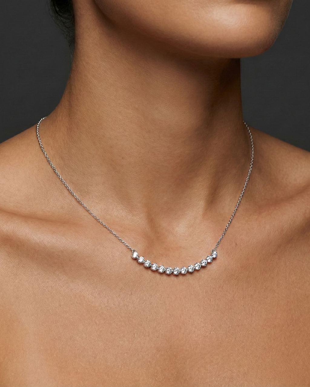 Lifestyle view of a white gold necklace worn on the neck, showcasing round white diamonds along a curved design.