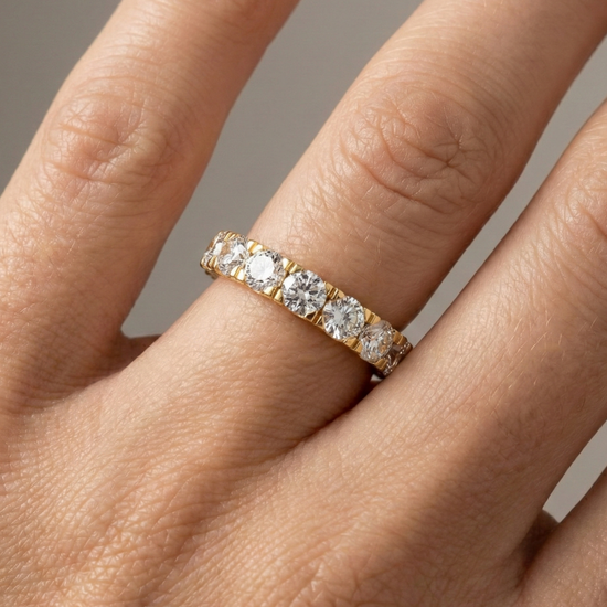 A magnificent 14k yellow gold eternity band featuring a continuous circle of 4.0 total carats of brilliant round-cut lab-grown diamonds on hand.