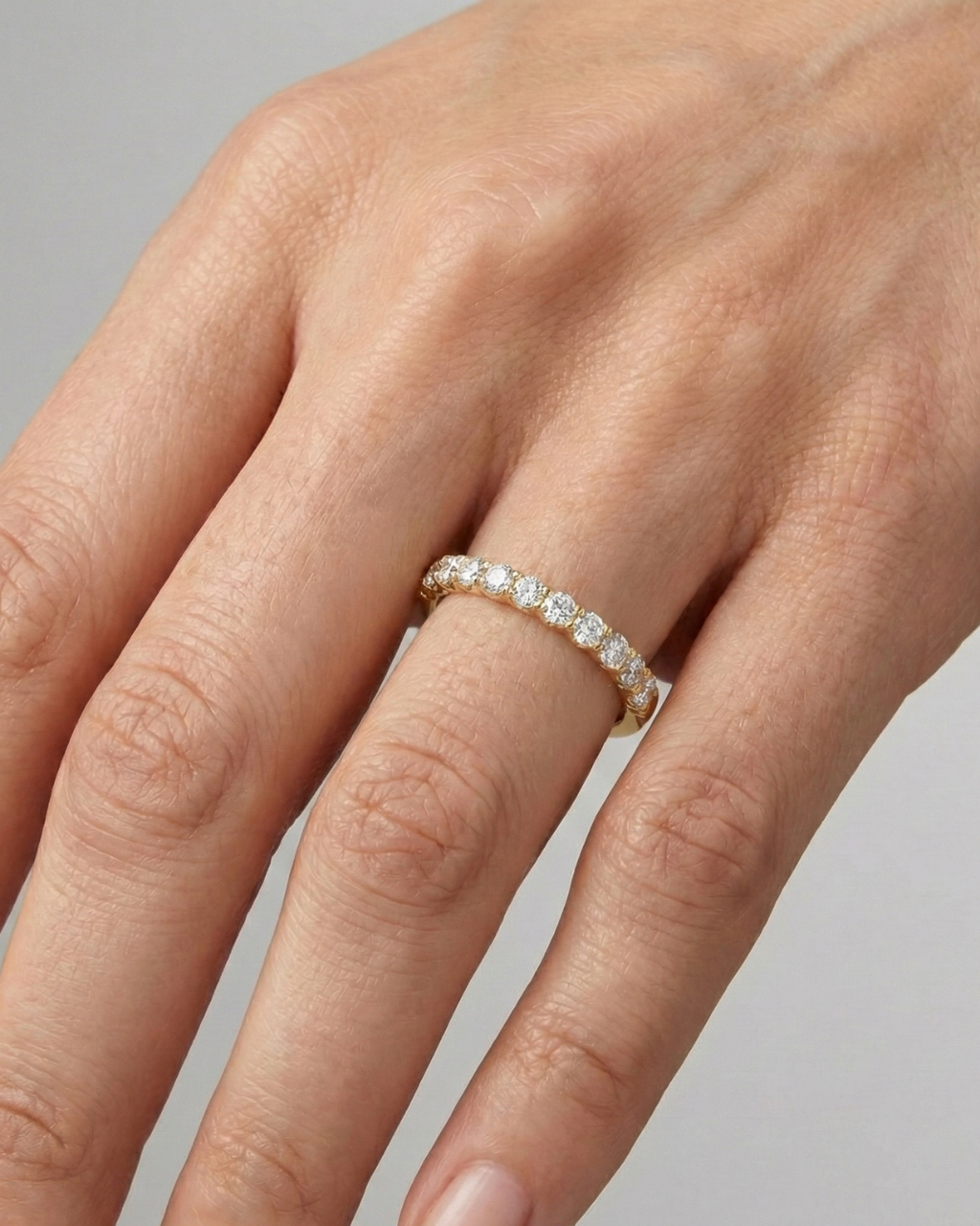 A delicate 14k yellow gold wedding band featuring 0.33 total carats of round-cut lab-grown diamonds in a classic half eternity setting on hand.