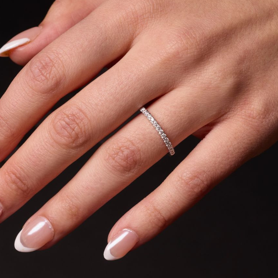 A delicate 14k yellow gold wedding band on a hand featuring 0.25 total carats of radiant round-cut lab-grown diamonds in a classic half eternity setting.