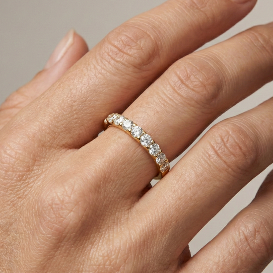 A dainty 14k yellow gold wedding band featuring 0.50 total carats of round-cut lab-grown diamonds in a classic half eternity setting on hand.
