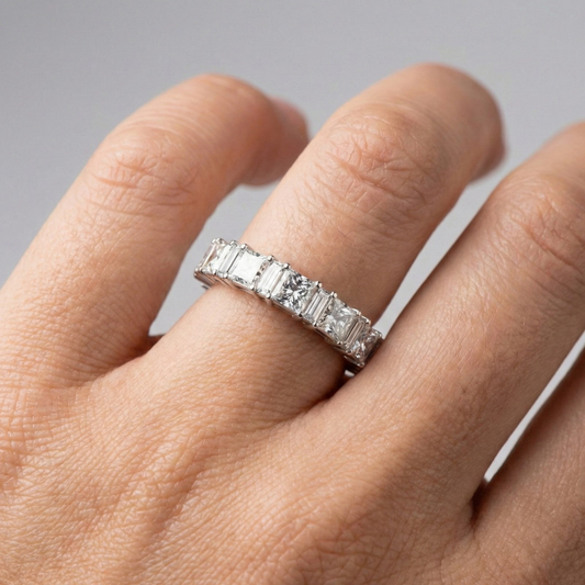 A top-down view of a 14K white gold eternity ring with a continuous line of horizontally-set princess-cut diamonds on hand.