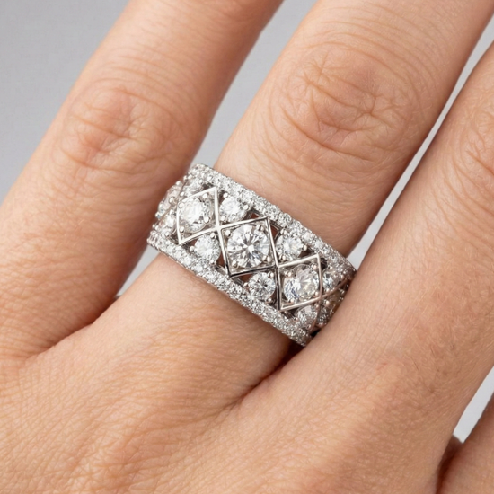 A top-down view of a 14K white gold wide band ring with a geometric pattern of princess-cut and pavé diamonds on hand.