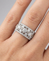 A top-down view of a 14K white gold wide band ring with a geometric pattern of princess-cut and pavé diamonds on hand.