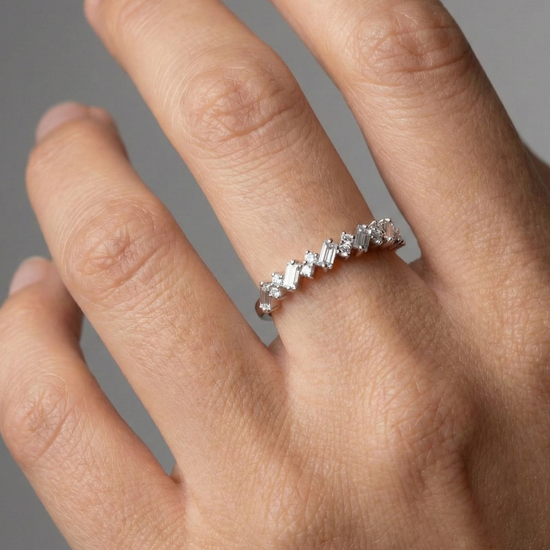 A top-down view of a 14K white gold band ring with an alternating pattern of baguette and round diamonds on hand.