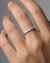 A top-down view of a 14K white gold band ring with an alternating pattern of baguette and round diamonds on hand.