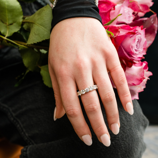 A top-down view of a 14K yellow gold wide band ring with a continuous row of large, bezel-set round jewels on hand.