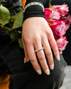 A top-down view of a 14K yellow gold wide band ring with a continuous row of large, bezel-set round jewels on hand.