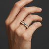 A top-down view of a 14K yellow gold wide-band ring with five horizontally set emerald-cut diamonds on hand.