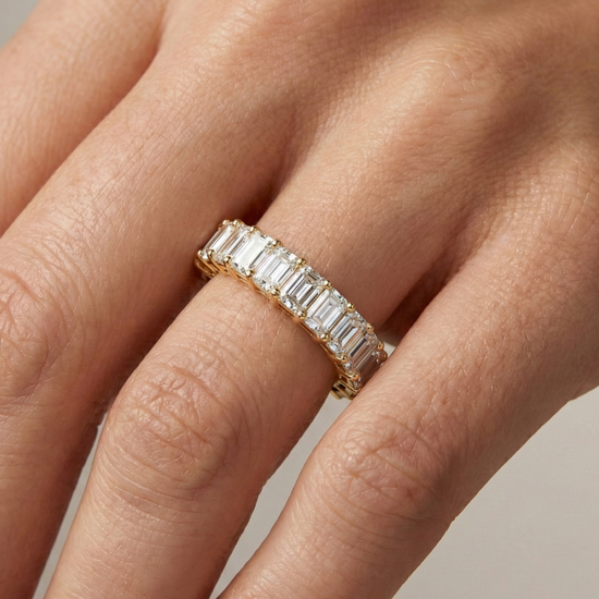A breathtaking 14k yellow gold full eternity band featuring a continuous circle of 2.3 total carats of shimmering emerald-cut lab-grown diamonds on hand.