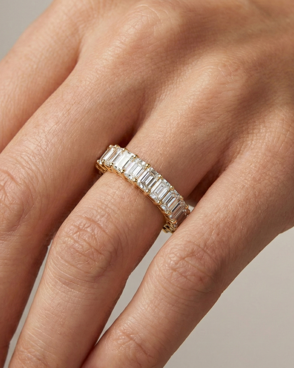 A breathtaking 14k yellow gold full eternity band featuring a continuous circle of 2.3 total carats of shimmering emerald-cut lab-grown diamonds on hand.