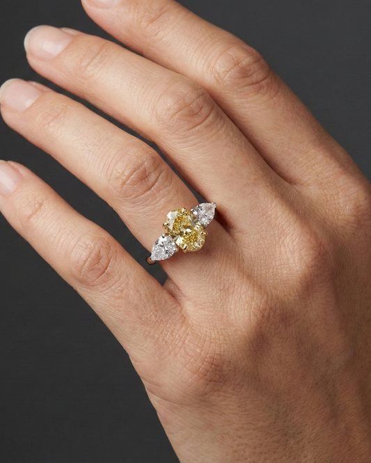 Close-up hand view of a 3.20 Cttw. Soleil Oval Canary Yellow and White Diamond Trilogy Engagement Ring, featuring a 2-carat Vivid Canary center stone and two 0.60ct white diamond side stones set in 14K gold.
