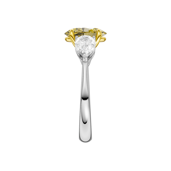 Side view of a white gold three-stone ring highlighting the elevated yellow diamond center and tapered pear-shaped white diamond accents.
