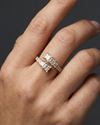Close-up of a hand wearing a 14k yellow gold open diamond ring featuring princess-cut diamonds set across a modern, split-band design, photographed against a dark background to highlight clean lines, refined sparkle, and contemporary elegance.