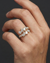 Close-up of a hand wearing a 14k yellow gold diamond statement ring featuring a clustered arrangement of mixed-cut diamonds, photographed against a dark background to emphasize dimensional sparkle, modern design, and elevated craftsmanship.