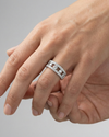 A top-down view of a 14K white gold wide band ring with three rows of pavé diamonds on hand.