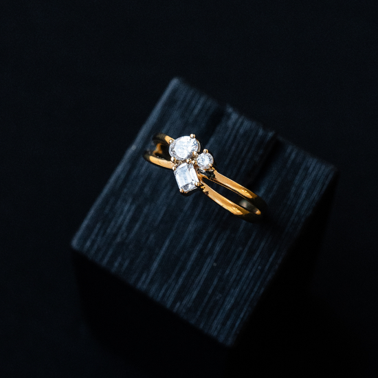 Yellow gold architectural diamond cluster ring featuring mixed-cut diamonds, resting on a black textured display block.