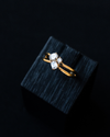 Yellow gold architectural diamond cluster ring featuring mixed-cut diamonds, resting on a black textured display block.